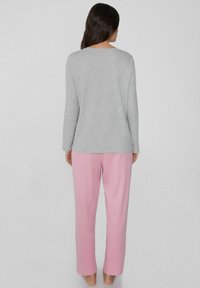 Top gris de mangas largas y pantalones rosa claro, hechos de una tela suave. El top tiene un escote redondo; los pantalones son holgados con una cinturilla elástica.