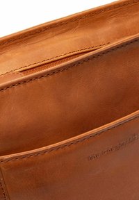 Bruine leren portemonnee met een soepele textuur, voorzien van een ritsvak en een reliëflogo. Netjes gestikte randen.