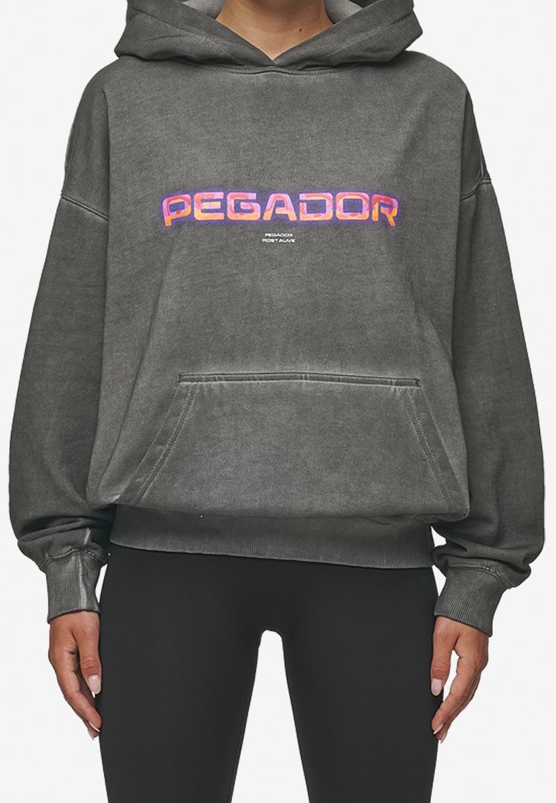 Sudadera gris de gran tamaño en tela suave con un bolsillo frontal. Presenta "PEGADOR" en letras brillantes y multicolores en el pecho.