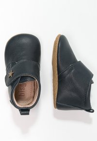 Mörkblå läderskor för småbarn med en kardborreknäppning och stjärndetalj, som har en mjuk innersula och flexibel brun gummisula.