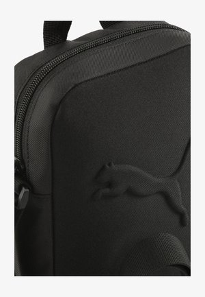 Schwarzer Stoff-Rucksack mit strukturiertem Logo, glattem Reißverschluss und robustem Griff; minimalistisches Design mit einer schlanken, modernen Optik.