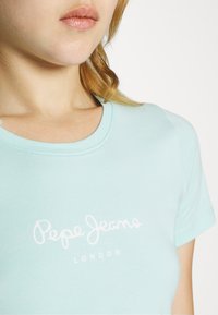 Svijetloplavi majica s kratkim rukavima od pamuka s okruglim izrezom. Na prsima se nalazi bijeli tiskani natpis "Pepe Jeans LONDON".