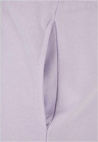 Lys lilla stoff med jevn tekstur, som har en sidelomme integrert i designet. Enkel, tettsittende form med pene sømmer.