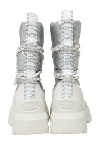 Zapatillas de plataforma blancas con parte superior acolchada brillante en plata, cordones de cuerda y tiras reflectantes de marca. Suela sólida con detalles sutiles en textura.