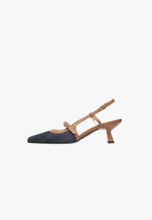 Chaussure slingback à bout pointu avec talon bas, avant en denim foncé et brides en cuir marron avec boucles sur fond blanc.