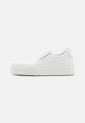 Hvid slip-on plateau sneaker med glat læderoverdel og tyk gummisål, vist i profil mod en ensfarvet baggrund.