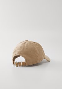 Tan kordfløyels baseball cap med buet skjerm, teksturert stoff og justerbart lærreim med metallspenne bak.