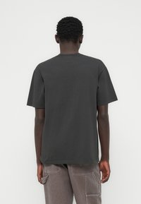 Σκούρο γκρι  βαμβακερό T-shirt με στρογγυλή λαιμόκοψη και κοντά μανίκια· διαθέτει άνετη εφαρμογή και χωρίς γραφικά ή σχέδια στην πλάτη.