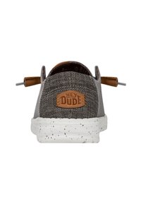 Scarpa di tessuto grigia con accento in pelle marrone, suola bianca maculata e un'etichetta prominente; presenta lacci elastici e un design con retro basso.