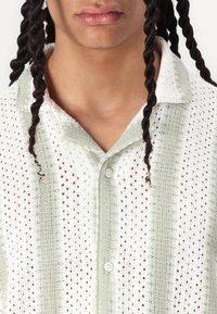 Lichtgewicht, opengeweven shirt in wit en lichtgroene strepen, met een kraag en knoopsluiting. Textuurstof met een ontspannen pasvorm.