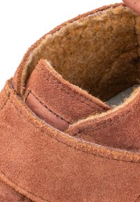 Zapato de ante marrón con un upper suave y texturizado, con un acento cosido alrededor del collar y un forro interior bien terminado.