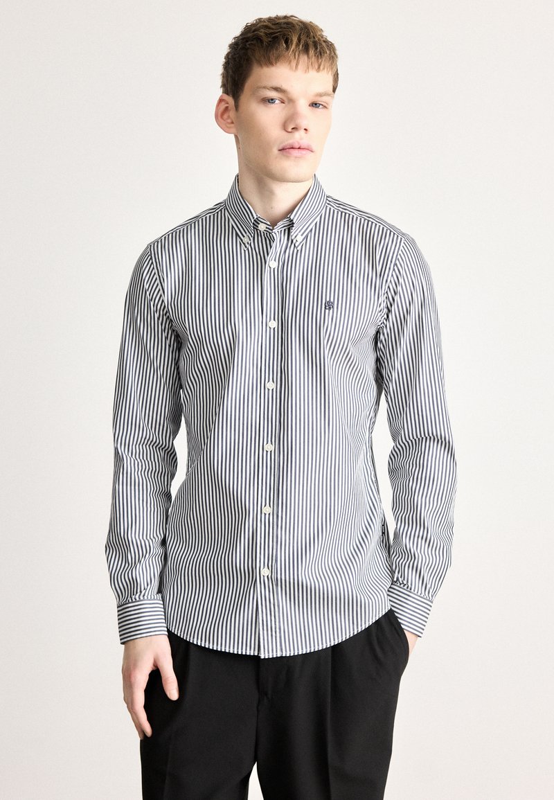 Ελαφρύ πουκάμισο με στενές μπλε και λευκές ρίγες. Διαθέτει μυτερό γιακά και μανίκια με μανσέτες. Κέντημα με λογότυπο στο στήθος.