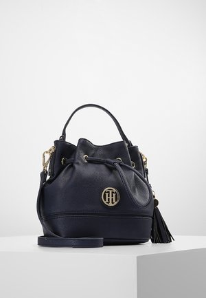Kleine dunkelblaue Ledertasche in Bucket-Form mit Zugkordelverschluss, goldfarbenem Logoemblem, Quasten-Detail, oberem Griff und abnehmbarem Schulterriemen.