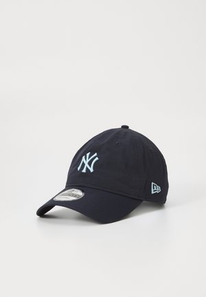 Marineblå bomulds-kasket med et frontlysblåt broderet "NY" logo og et sidelogo-tag. Har en buet skygge og en tekstureret stoffinish.