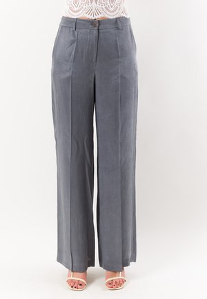 Pantaloni grigi a vita alta con gamba larga e piega centrale, chiusura con bottone e zip, indossati con sandali bianchi con tacco e cinturini.