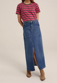 Randig kortärmad skjorta i rosa och olivgrönt, ihop med en figurnära denim-maxijskirt med en sidoflik och fyra fickor. Bruna ankelstövlar.