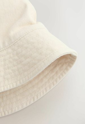 Cappello a secchiello beige chiaro realizzato in tessuto testurizzato, con tesa ampia e leggermente floscia e dettagli di cuciture sottili.