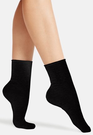 Schwarze Knöchelsocken aus weichem Material, mit einem gerippten Bund und glatter Textur, die dafür entworfen sind, eng am Knöchel zu sitzen.