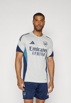 Grå og navy atletisk trøje med korte ærmer, med "Emirates Fly Better" logo og Adidas striber. Matcher med navy shorts.