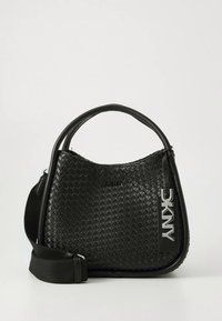 Melna austā ādas rokassoma ar regulējamu siksnu, apaļu augšu un izteiktu DKNY logotipa zīmīti. Roktura virsma ir teksturēta.