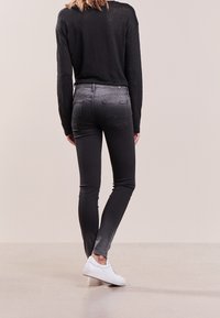 Cienkie dżinsy w ciemnoszarym deniźie z wyblakłym wykończeniem, z tylnymi kieszeniami i średnim stanem. Połączone z białymi sneakersami.