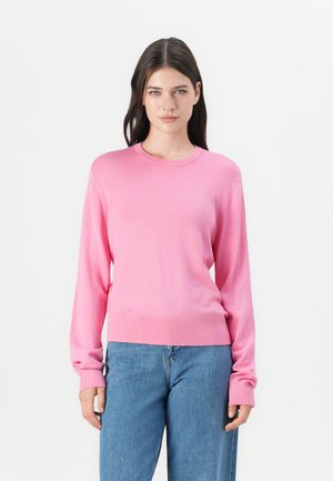 Maglione rosa a maniche lunghe in maglia leggera, con collo a girocollo, polsini e orlo a coste, abbinato a jeans blu dal taglio comodo.
