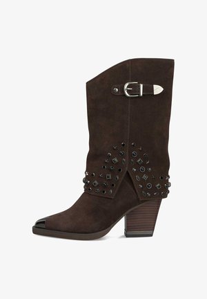 Bottine en suede marron avec un bout pointu, des accents cloutés et une boucle en argent. Dispose d'un talon empilé et de détails texturés.