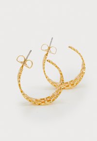 Gylne hoops øredobber med laserutskåret design og teksturert overflate, sikret med en metalllåsing og preget av en åpen struktur.