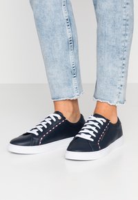 Sneakers in pelle blu navy con lacci bianchi, cuciture a contrasto e suole in gomma testurizzata, con un logo sul lato.