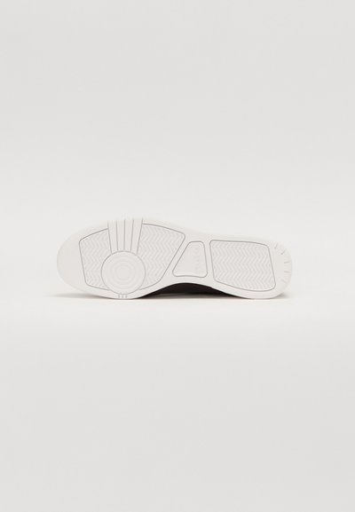 Semelle de sneaker blanche avec un motif texturé, présentant des accents circulaires et un design flexible. Matériau en caoutchouc avec une finition lisse.