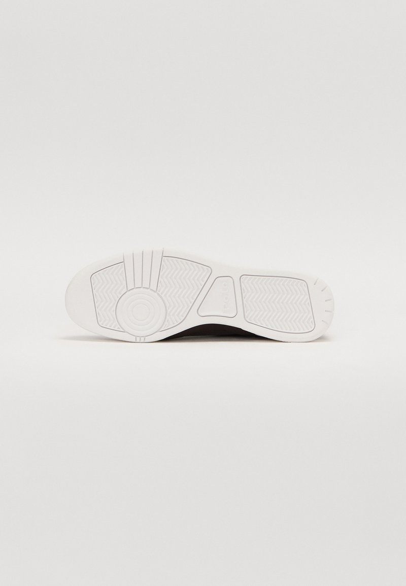 Semelle de sneaker blanche avec un motif texturé, présentant des accents circulaires et un design flexible. Matériau en caoutchouc avec une finition lisse.