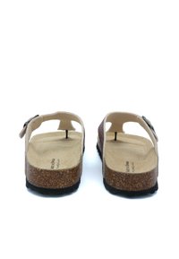 Deux sandales avec une semelle en liège et une semelle intérieure beige. Le dessus arbore une sangle texturée rose et une boucle noire réglable.