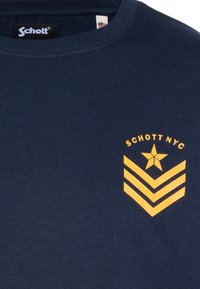 Granatowy, bawełniany t-shirt z krótkim rękawem i okrągłym dekoltem, z żółtą gwiazdą i wzorem w jodełkę po lewej stronie.