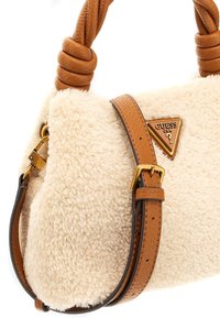Borsa in tessuto color crema con una texture morbida e pelosa. Presenta una tracolla in pelle marrone e accenti dorati, incluso un'incisione del logo.