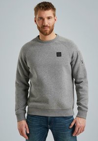 Grauer Pullover aus weichem Stoff mit Rundhalsausschnitt, gerippten Bündchen und Saum, mit einem kleinen schwarzen Logo-Patch auf der Vorderseite.