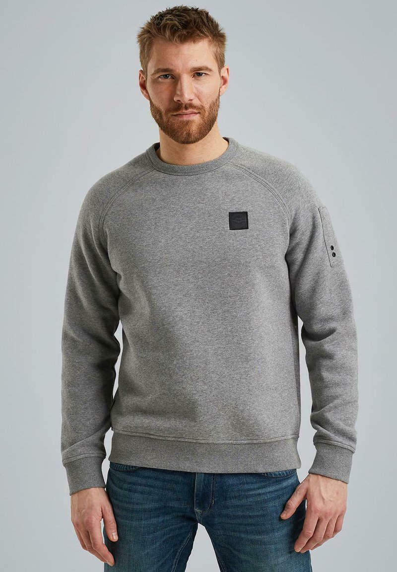 Grauer Pullover aus weichem Stoff mit Rundhalsausschnitt, gerippten Bündchen und Saum, mit einem kleinen schwarzen Logo-Patch auf der Vorderseite.