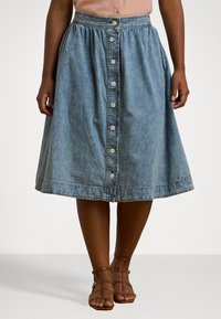 Jeanskjørt med en utsvingt design, knappelukking foran og en lyseblå farge med en falmet tekstur.