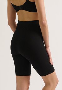 Zwarte geribde fietsshorts van rekbaar materiaal, met een hoge taille en een aansluitend ontwerp, dat net boven de knie eindigt.