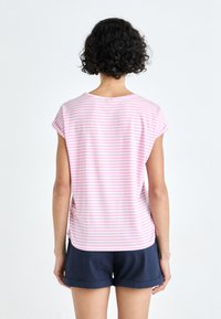 Rosarandig kortärmad T-shirt i mjuk bomull, med rundad halsringning och avslappnad passform, matchad med marinblå shorts.