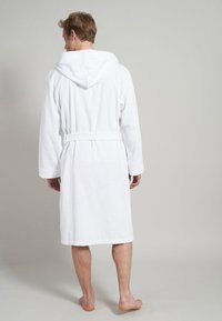 White cotton bathrobe with a hood, belted waist, and long sleeves. The fabric appears plush and absorbent, with a knee-length cut.