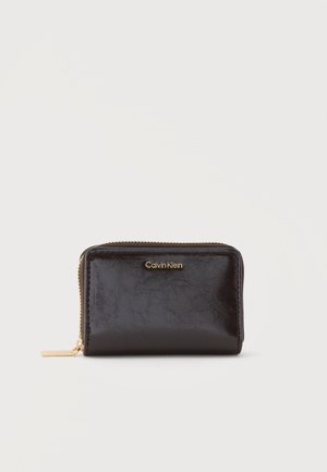 Kompakt sort læderpung med guldfarvet lynlås og Calvin Klein logo præget foran i midten.