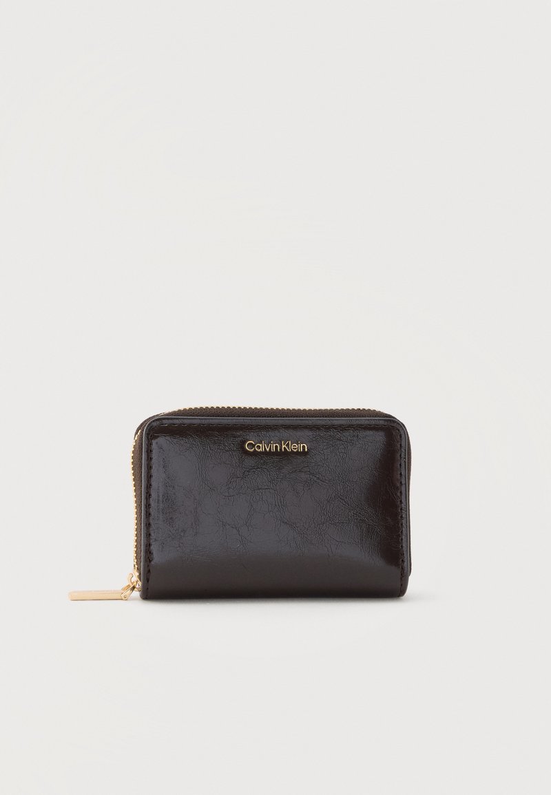 Portefeuille compact en cuir noir avec fermeture éclair dorée et logo Calvin Klein embossé au centre devant.