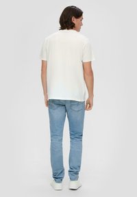 Biała koszulka z krótkim rękawem w połączeniu z jasnoniebieskimi dżinsami. Luźny krój, gładka tekstura i prosty design bez logo lub grafik.