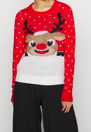 Czerwony sweter z białymi płatkami śniegu oraz dużą uśmiechniętą twarzą renifera z czerwonym nosem, noszony z czarnymi spodniami.