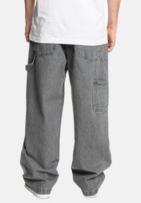 Grå denim cargo bukser med en afslappet pasform, flere lommer og synlige syninger. Let falmet struktur, afsluttet med en tætsiddende ben.