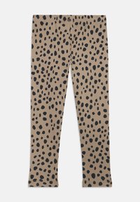 Legginsy w jasnobeżowym materiale z teksturowanym ryżowym wzorem, z dużymi, czarnymi, nieregularnymi kropkami w całej powierzchni. Dopasowany krój z otworami na kostki.