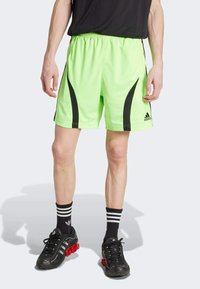 Neon green athletic shorts with black side accents and a lightweight design. Paired with black shoes and striped socks for a sporty look.