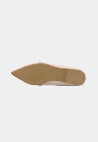 Chaussure à bout pointu avec une tige rose clair, une texture lisse, et une semelle fine couleur nude présentant un motif antidérapant léger.