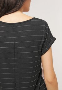 Czarny top z krótkim rękawem w białe poziome paski, z okrągłym dekoltem i miękkim, lekkim materiałem.