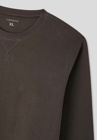 Felpa marrone scuro realizzata in tessuto morbido. Presenta un collo rotondo, polsini a coste e dettagli cuciti sulle spalle. Taglia XL.